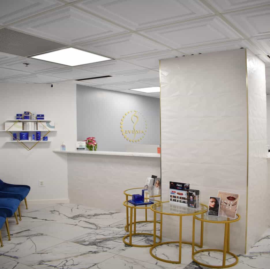 Evexia Medspa's lobby is welcoming and inviting with white walls and gold tables with brochures highlighting the many face and body services they offer in McLean.