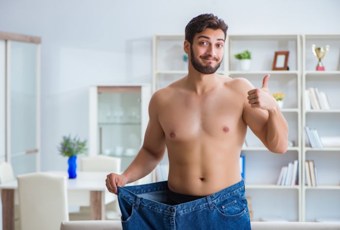 A man showing his lost weight from weight loss medication, a service offered at Evexia Medspa in Tysons Corner, VA.