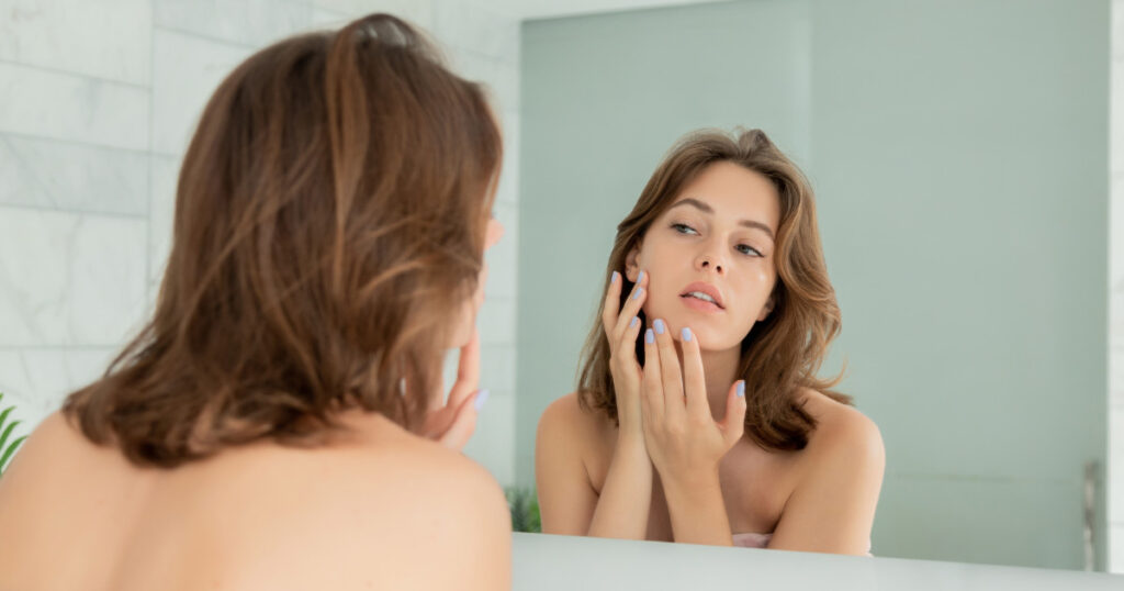 someone looking at their skin in a mirror 1024x538 1