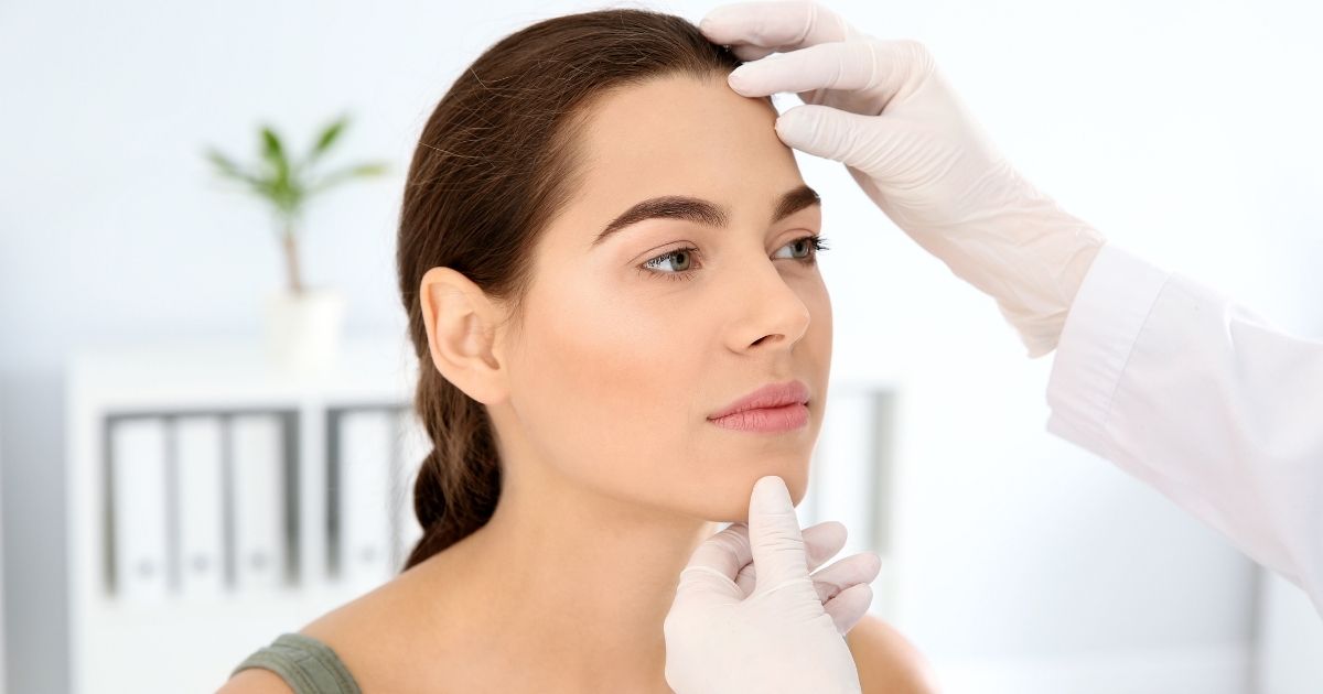 Provider assessing a woman's forehead during a Botox consultation.