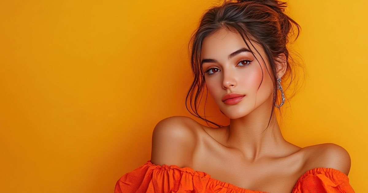 Young woman with smooth skin posing against a bright orange background