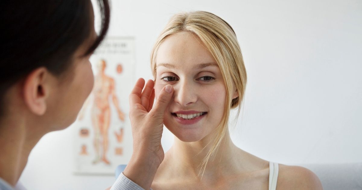 Cheek Filler vs. Jawline Filler: Which Creates Better Facial Balance? 4 Injector performing facial assessment, gently touching patient’s cheek and jawline while discussing treatment options