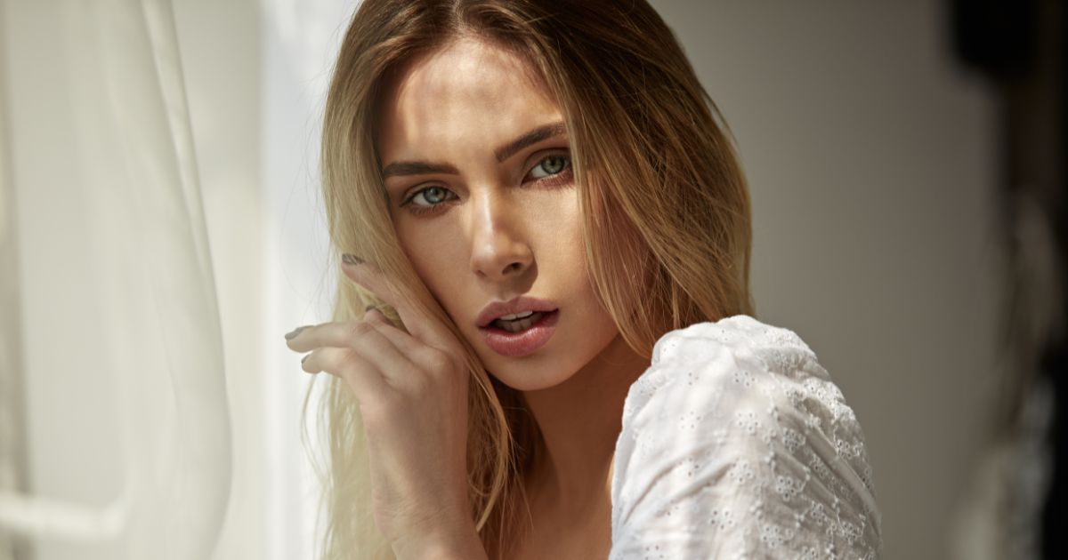 Woman with glowing skin posing in soft natural light.